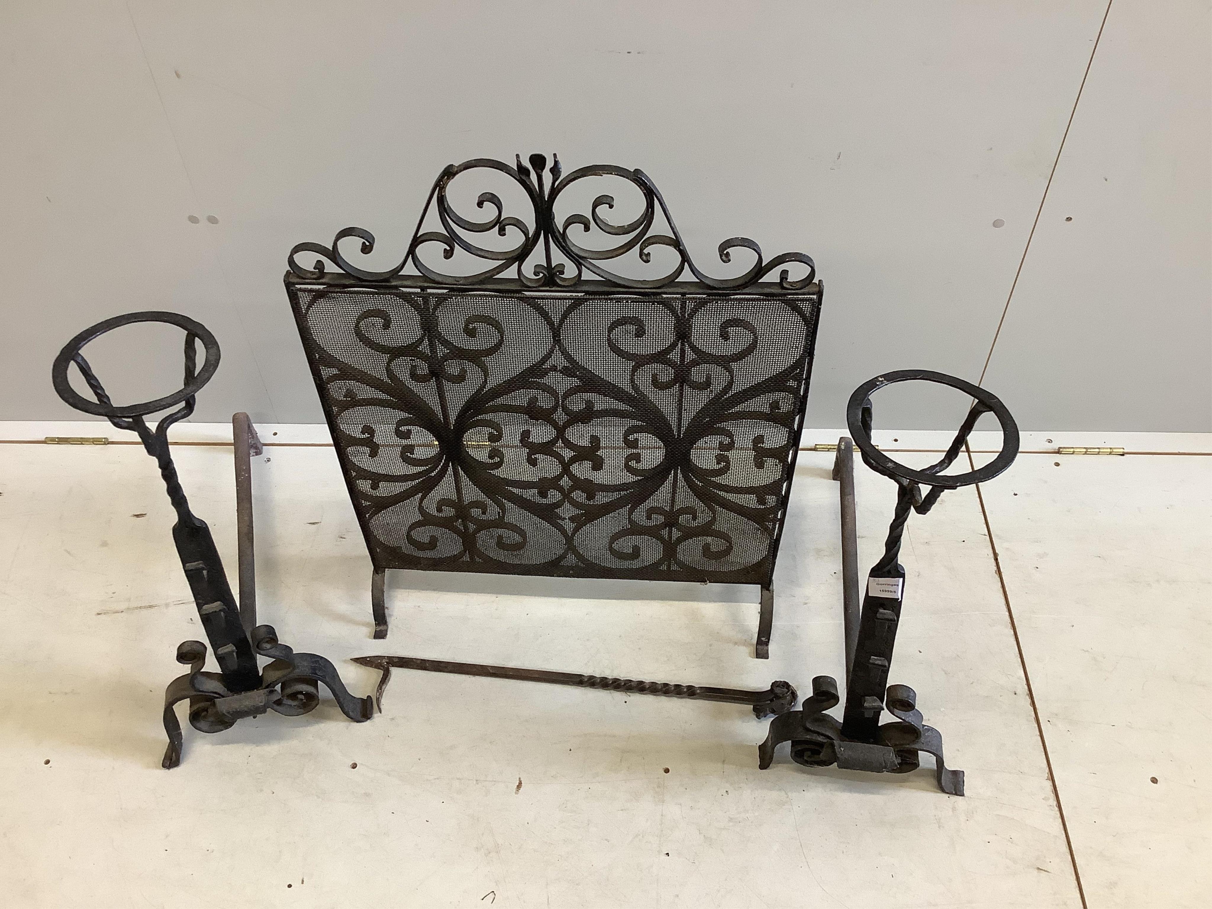 A pair of wrought iron fire dogs, with brazier finials, height 71cm, a wrought iron and wire mesh spark guard and a poker. Condition - fair